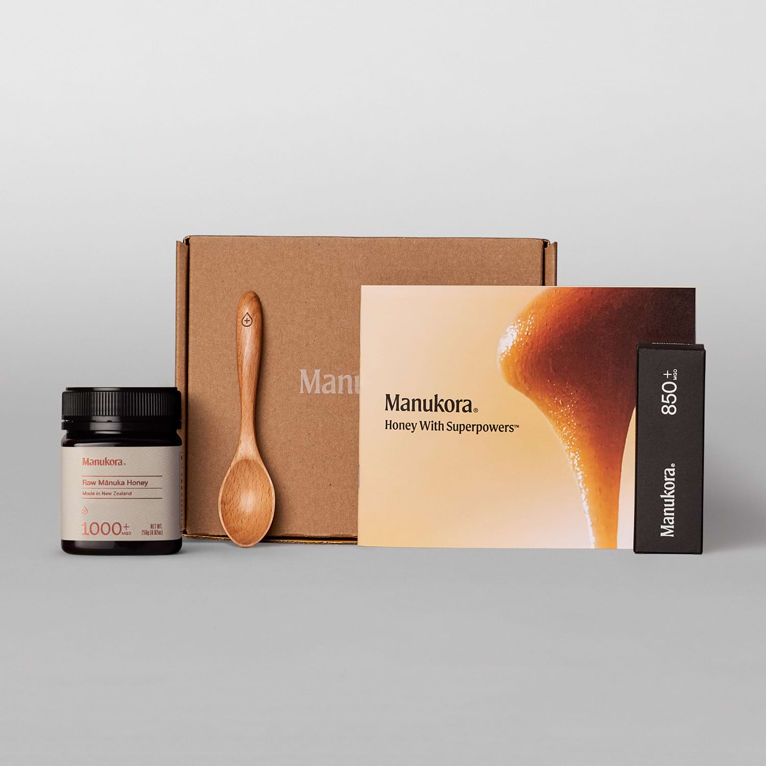 Manukora honey gift set with jar, brochure, packaging, and wooden spoon on display.