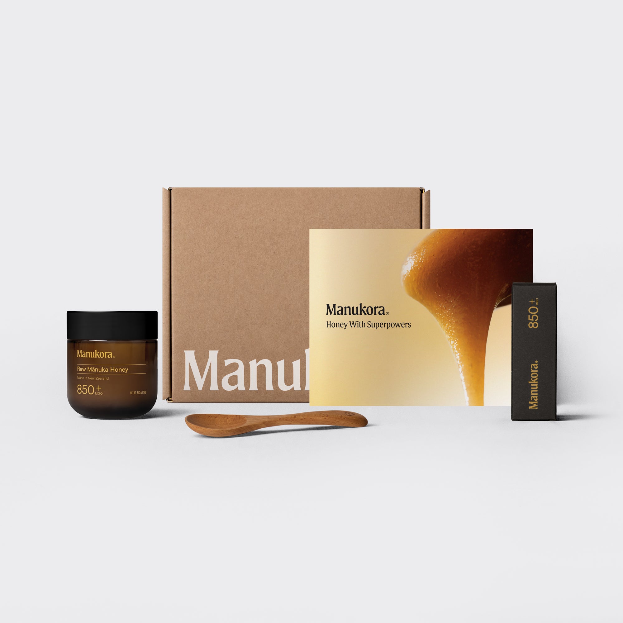 Manukora honey gift set with jar, brochure, packaging, and wooden spoon on display.