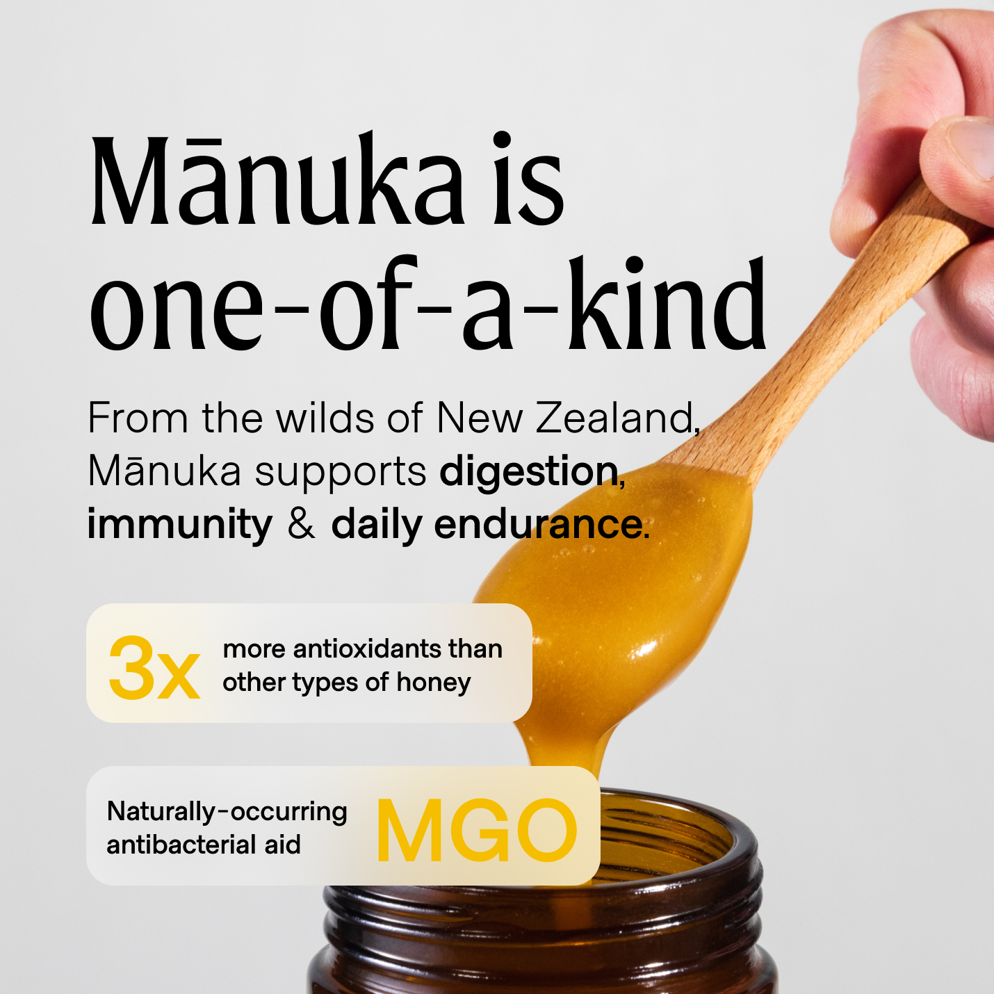 A hand holding a spoonful of Manukora raw Mānuka honey.
