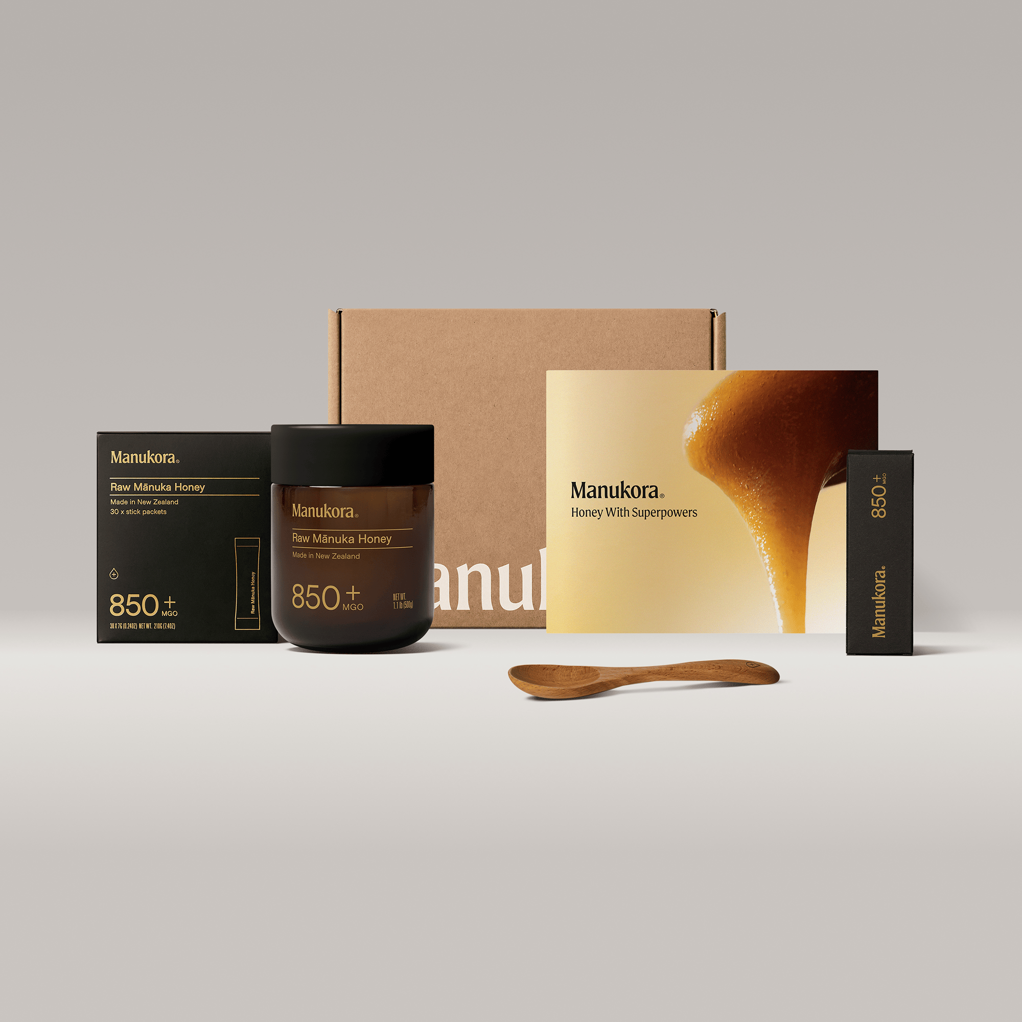 Manukora honey gift set with jar, brochure, packaging, and wooden spoon on display.