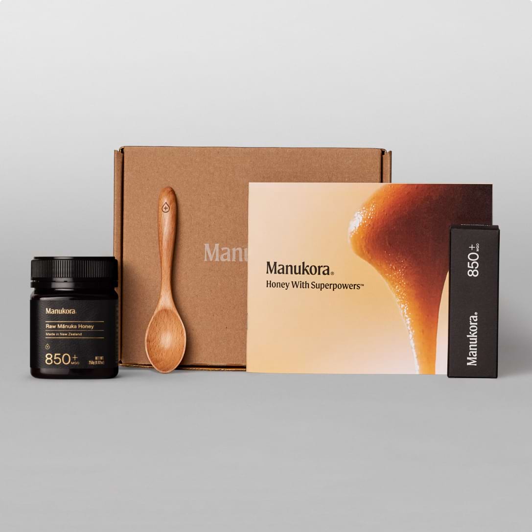 Manukora honey gift set with jar, brochure, packaging, and wooden spoon on display.